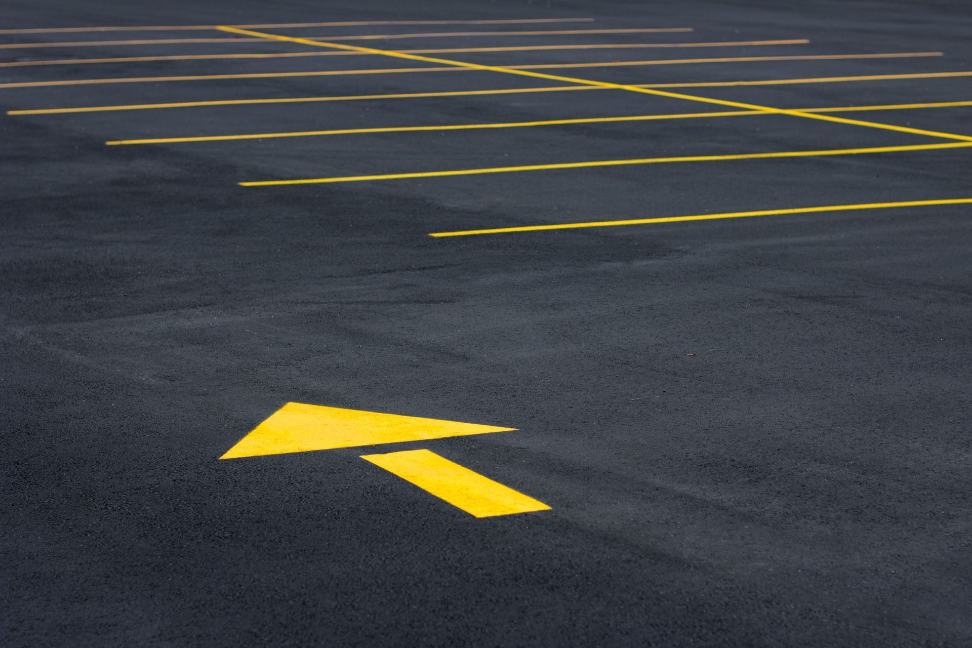 Yellow arrow striping on parking lot pavement